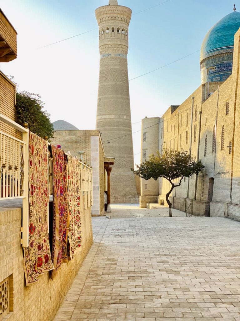 "Designed by Miran" suzani hanging on the wall on a streen of Bukhara.